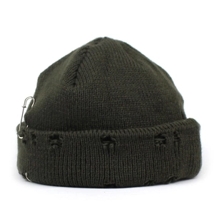 Detail of dark green knit beanie with ripped distressed texture and silver metal safety pin