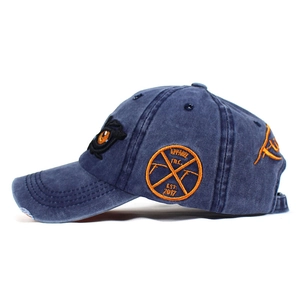 Detailed close-up of vintage navy washed cotton baseball cap with orange eagle eye embroidery