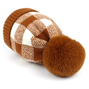 Detail of checkered knit beanie featuring a soft texture and fluffy brown pom-pom top