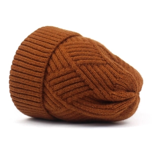 Detailed view of dark brown knitted beanie featuring textured cable knit pattern