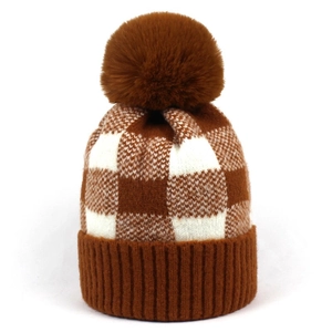 Detailed close-up of brown checkerboard knit beanie with a fluffy faux fur pompom detail