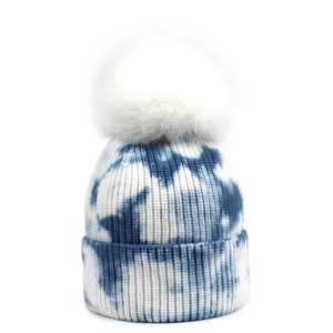 Détail du bonnet en tricot tie-dye bleu et blanc avec un pompon en fausse fourrure