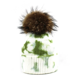 Détail du bonnet en maille tie-dye vert avec pompon duveteux et texture côtelée