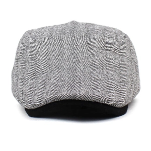 Macro shot of wool blend beret cap showing classic black and white herringbone pattern