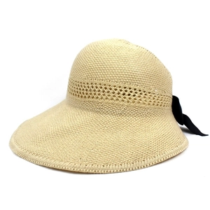 Detail of the elegant beige straw hat featuring geometric openwork weave and a black bow