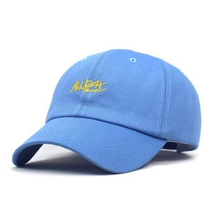 Detail of blue cotton baseball cap featuring yellow ALLDAY embroidery and fine stitching