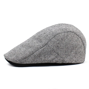 Detailed macro view showing grey herringbone wool pattern on the side of a flat cap