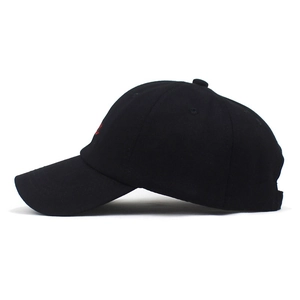 Detail view of black cotton baseball cap with red embroidered logo and breathable eyelets