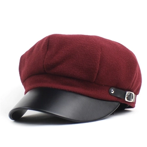 Detail view of burgundy wool newsboy cap with black leather brim and silver buckle