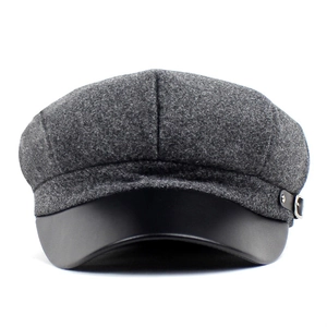 Close-up of wool newsboy hat featuring a leather brim and metallic buckle details
