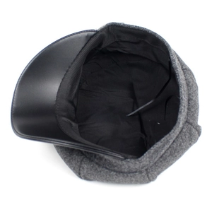 Gray wool newsboy cap with black faux leather brim and inner lining detail on white background