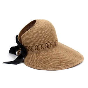 Detail of camel straw sun hat featuring a large black ribbon bow and open top design