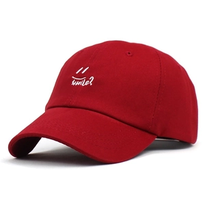 Detail of dark red cotton baseball cap featuring white smile embroidery and smile? text