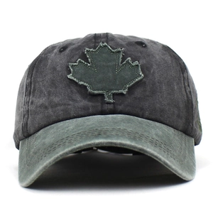 Close-up of washed gray cotton baseball cap with green maple leaf patch and visor details