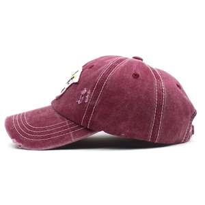 Side view detail of burgundy washed cotton baseball cap with vintage distressed effects