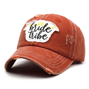 Detail of vintage washed brick red baseball cap featuring bride tribe embroidery and distressed holes