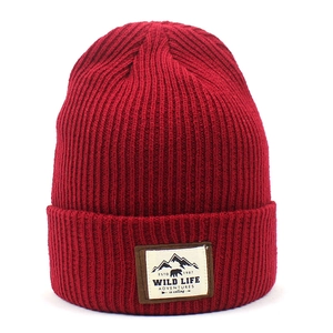 Detailed close-up of dark red ribbed knit beanie with mountain and bear patch embroidery