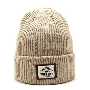 Beige ribbed knit beanie featuring an outdoor bear patch for winter warmth and fashion