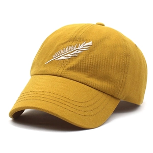 Détail de la broderie plume blanche sur une casquette de baseball en coton jaune moutarde