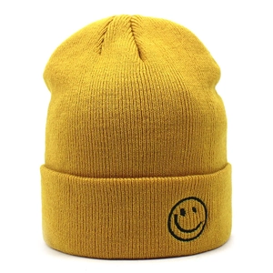 Dettaglio del berretto in maglia gialla con ricamo a forma di sorriso sul risvolto
