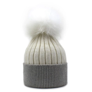 Close-up of contrast knit hat featuring grey fold-over cuff and white fluffy pompom