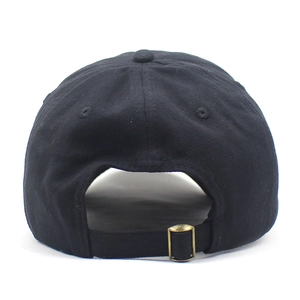 Détail d'une casquette en coton noir montrant la sangle réglable et la boucle dorée