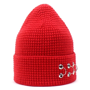 Détail du bonnet rouge en maille avec anneaux métalliques argentés sur le revers tendance