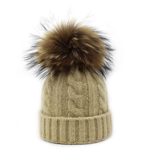 Detailed cable knit pattern on a winter wool beanie featuring a fluffy pom pom
