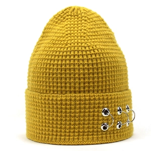 Détail du bonnet en maille moutarde avec texture nid d'abeille et anneaux argentés