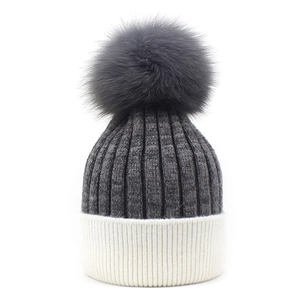 Women's two-tone knit beanie in dark grey and white with a large fluffy pom-pom