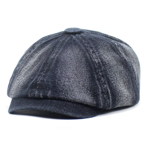 Macro detail of dark blue washed denim newsboy cap showing textured fabric and stitching