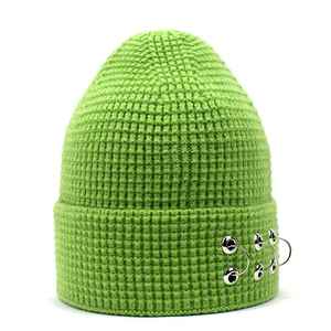 Détail du bonnet en maille verte avec texture gaufrée et trois anneaux métalliques argentés