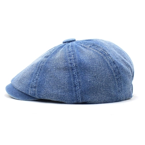 Close-up of blue washed denim newsboy cap showing textured octagonal stitching and top button