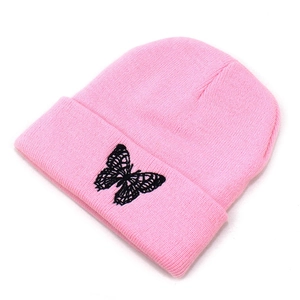 Detailed view of pink knitted beanie featuring black butterfly embroidery on cuff