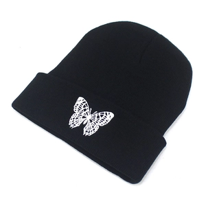 Detailed view of white butterfly embroidery on a black ribbed knit beanie cuff