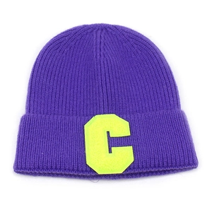 Dettaglio di un berretto in maglia viola con un vivace inserto a lettera C verde lime
