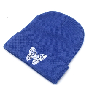 Close-up of blue ribbed knit beanie featuring detailed white butterfly embroidery on the cuff
