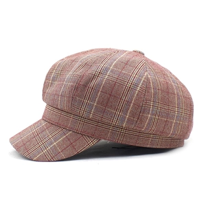 Detail view of red brown plaid octagonal cap with decorative top button and soft texture