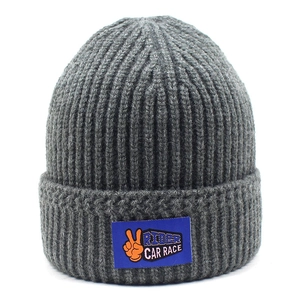 Detail of dark grey knit beanie featuring a blue logo patch with orange graphic