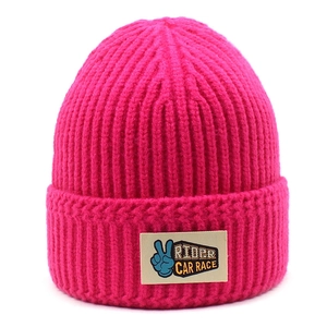 Detail of fuchsia ribbed knit beanie featuring a RIDER CAR RACE patch with victory gesture
