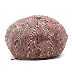 Detail of red-brown plaid newsboy cap with textured fabric and matching top button