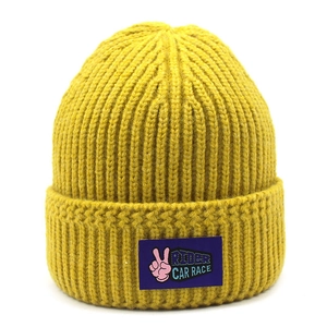 Close-up of mustard yellow knit beanie with purple rider patch and thick ribbed texture