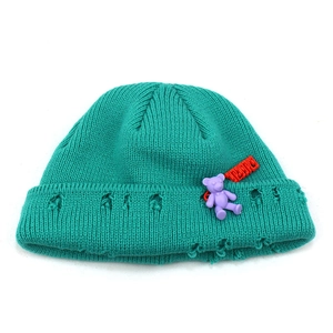 Detailed knit texture of lake blue beanie featuring distressed holes and a purple bear charm
