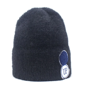 Detail van de zwarte gebreide muts met een blauwe UP letter borduursel patch