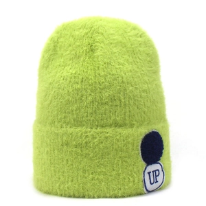 Detail van neongroene gebreide muts van imitatiebont met blauwe pompon en UP-letterbadge