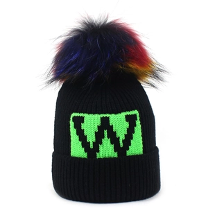 Berretto in maglia a coste nere con pompon in ecopelliccia colorata e toppa con lettera W