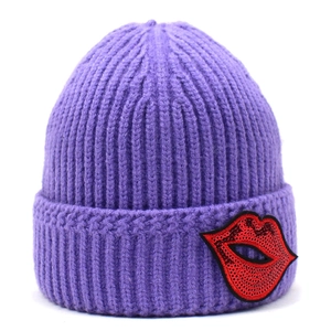 Dettaglio della toppa a labbra rosse con paillettes su un cappello a maglia viola