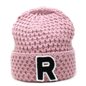 Nahaufnahme der rosa grob gestrickten Beanie mit gesticktem Buchstaben-R-Patch am Umschlag
