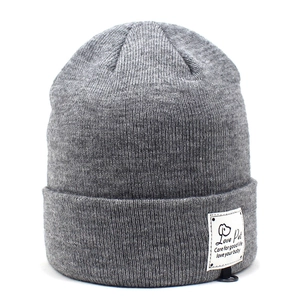 Detail of grey knitted beanie featuring thick vertical ribs and white logo brand label