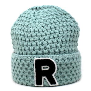 Detail der minzgrünen Strickmütze mit schwarzem R-Buchstaben-Patch und Rippenstruktur